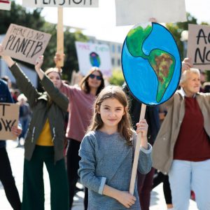 Nena en una manifestació aguanta una pancarta amb forma de planeta terra